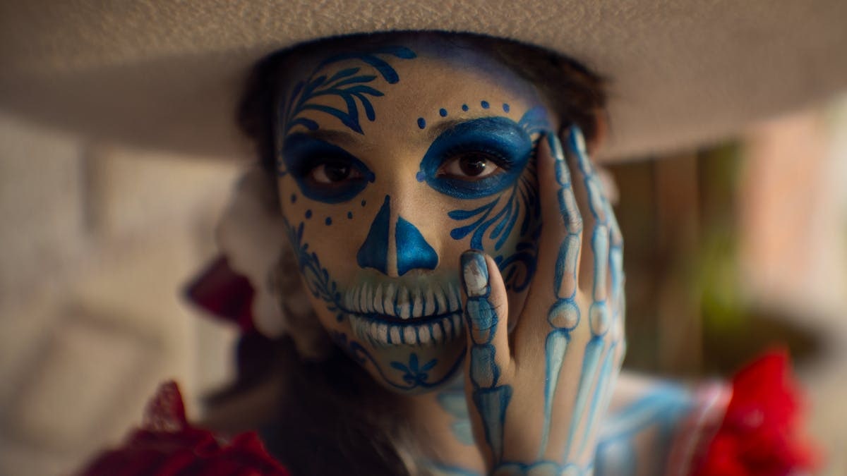 A woman in traditional Dia de los Muertos face paint in Mexico City, CDMX, Mexico.